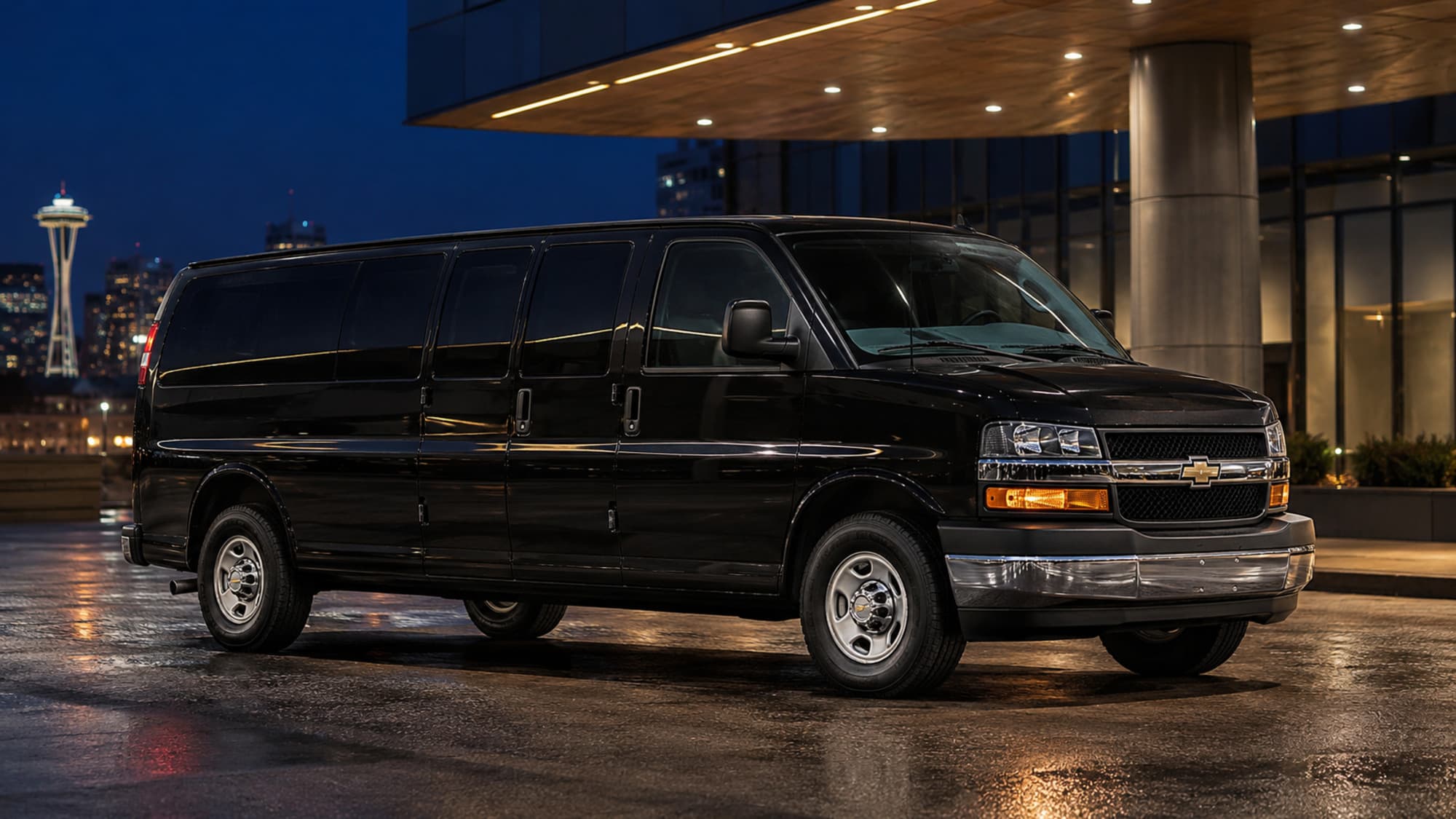 A black 2022 Chevrolet Express passenger van outside a waterfront building at night